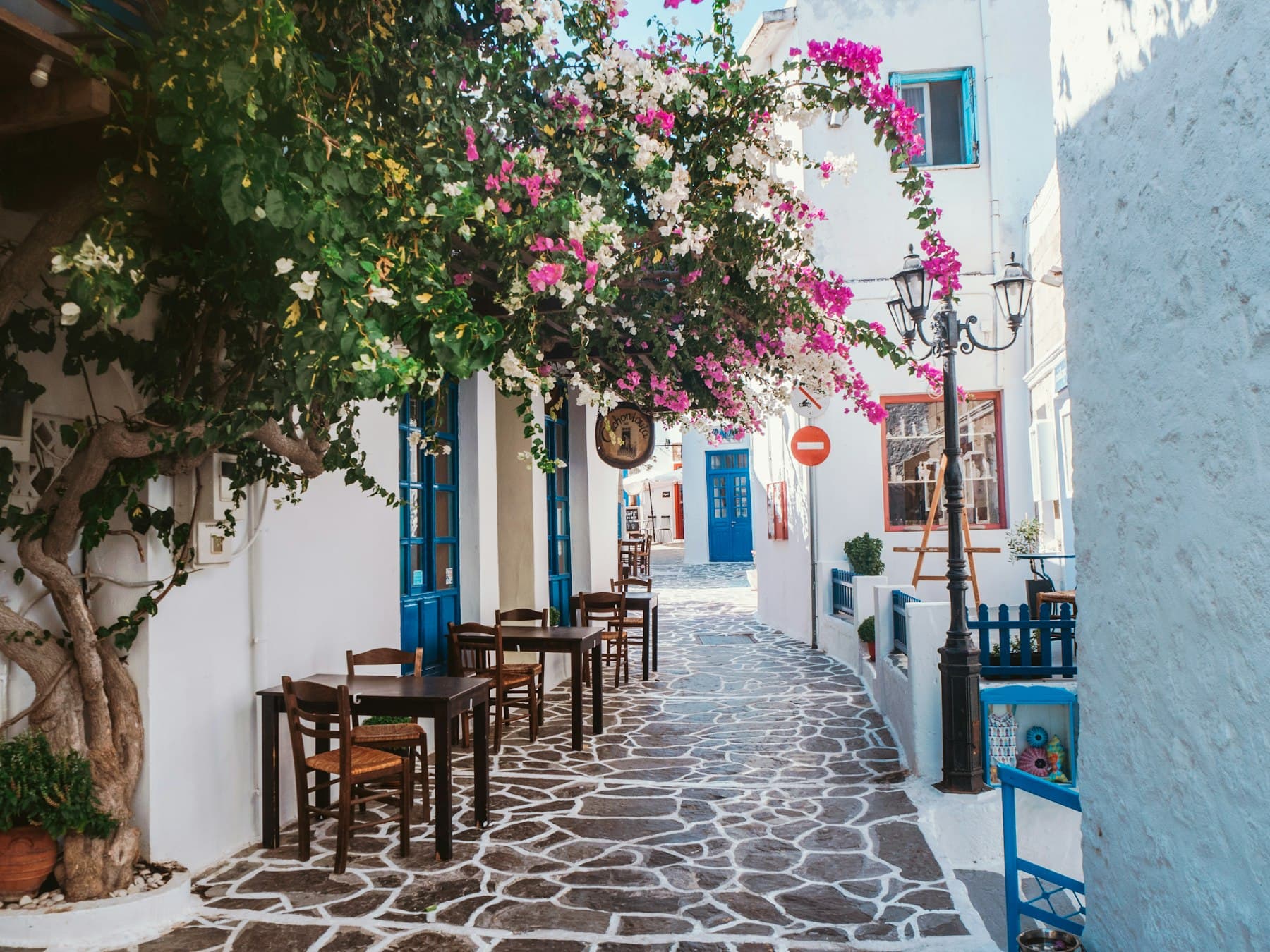 Bougainvillea hanging over a taverna terrace in a whitewashed Greek alley