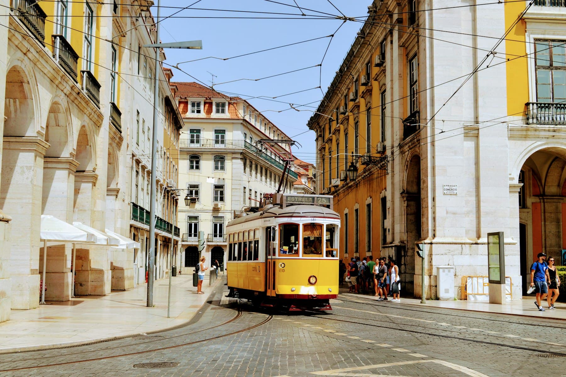 A yellow tram on a sunlit street in Lisbon