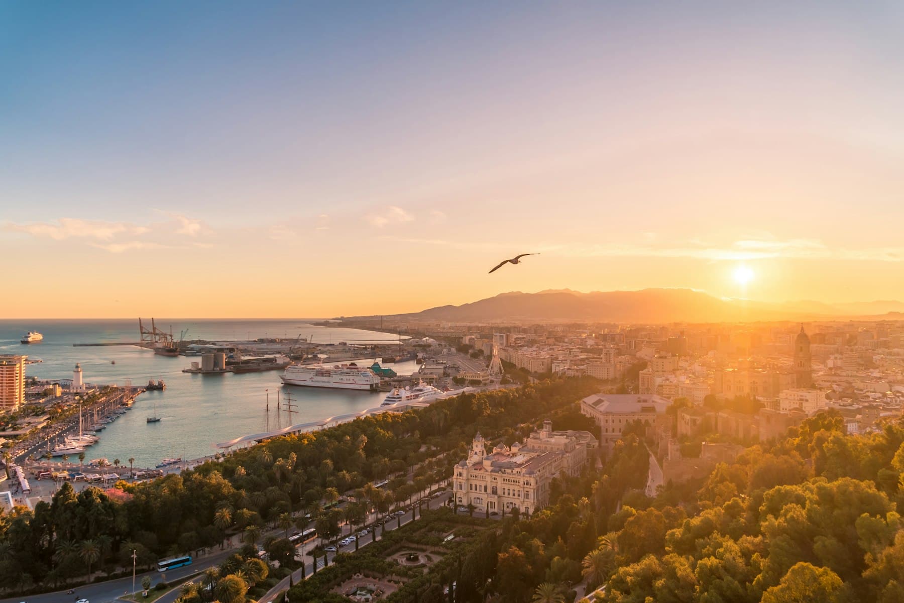 The sun going down over M谩laga, the port and the city under gold light