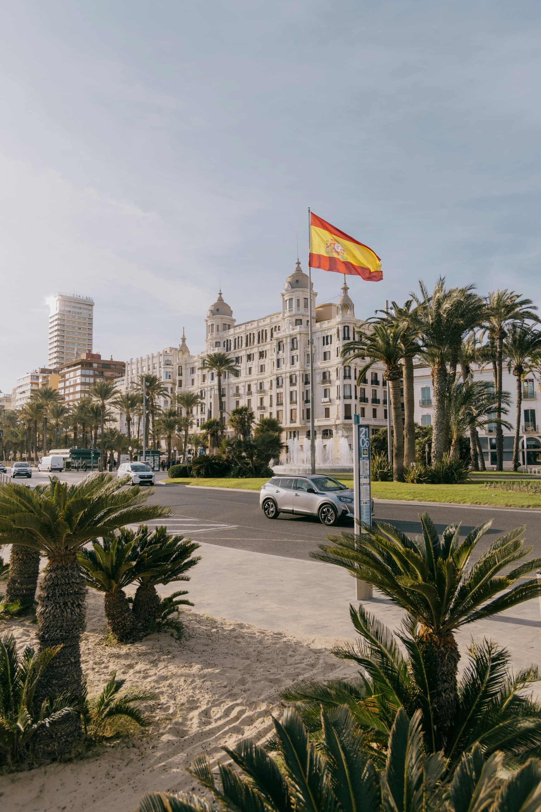 Palms and the Explanada promenade in Alicante under a Spanish flag
